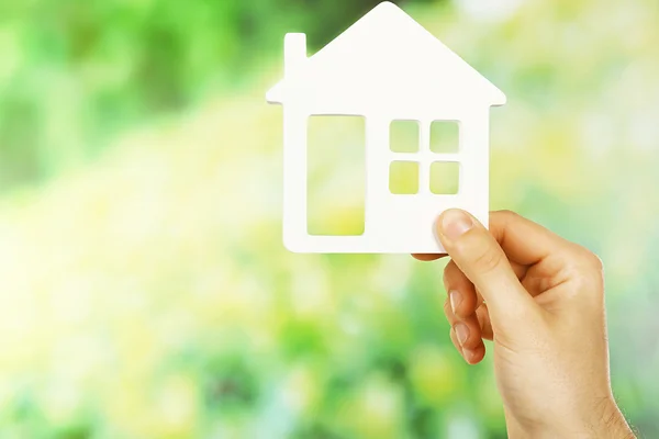 Femmina mano tenendo casa su sfondo verde sfocato — Foto Stock