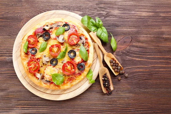 Pizza saborosa com legumes e manjericão sobre fundo de madeira — Fotografia de Stock