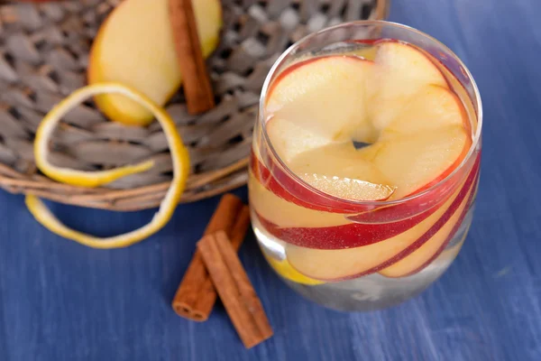 Glass of apple cider with fruits and cinnamon on table close up — Stock Photo, Image