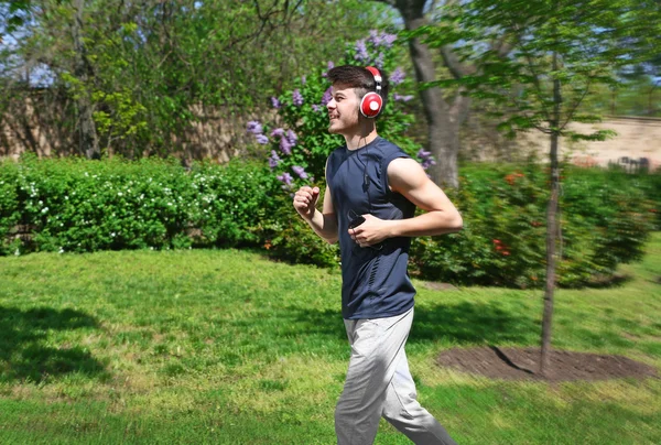 用耳机在公园慢跑的男人 — 图库照片