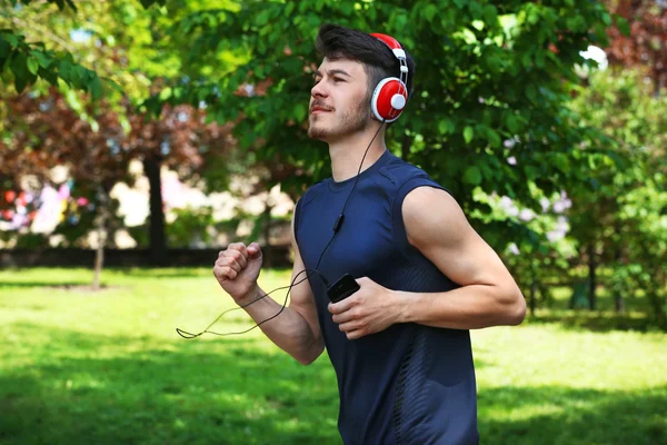 Hombre corriendo con auriculares en el parque — Foto de Stock