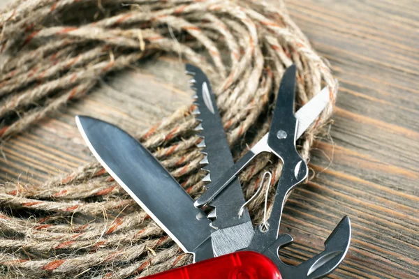 Pocket knife with rope on wooden table close up — Stock Photo, Image