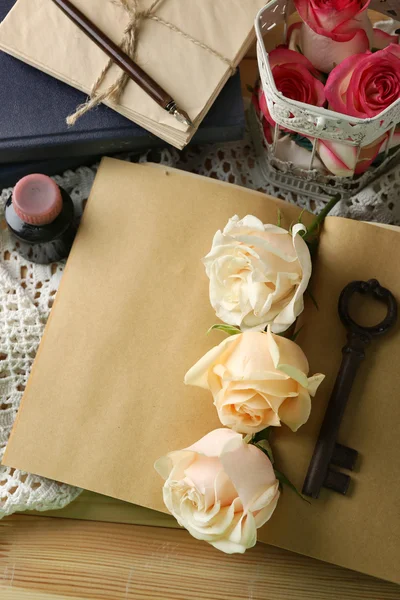 Ferske roser med gammel bok, nøkkel og bokstaver på trebordsbakgrunn. Årgangskonsept – stockfoto