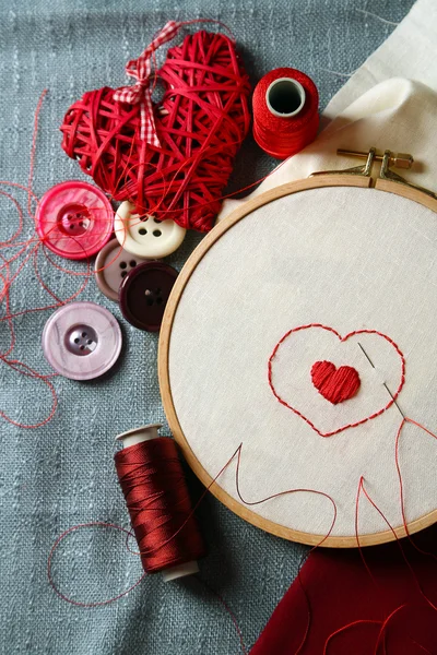 The embroidery hoop with canvas and red sewing threads on table close up — Stock Photo, Image