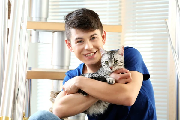 Handsome young man with cute cat sitting on steps at home — Stock Photo, Image