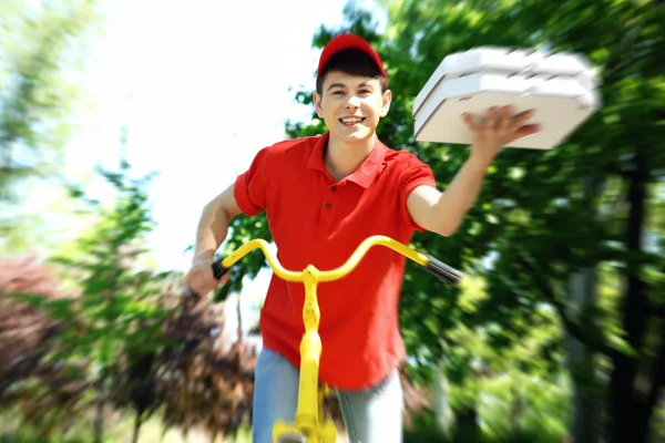 Mladý muž, dodávající pizza box na kole venku — Stock fotografie
