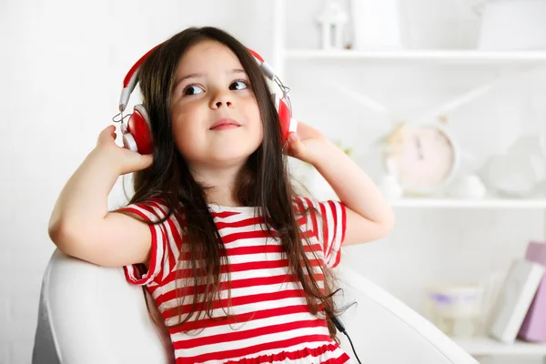 Beautiful little girl listening to music in room — Stock Photo, Image