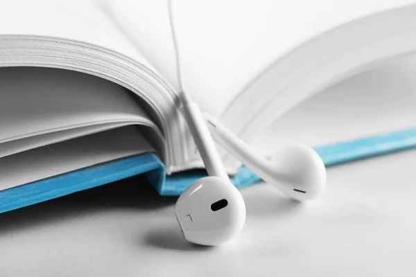 Earphones and book on table — Stock Photo, Image