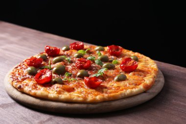 kiraz domates, yeşil zeytin ve siyah arka plan üzerine ahşap masa üzerinde otlar ile lezzetli pizza