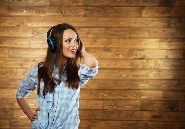 Young woman with headphones on wooden background — Stock Photo, Image
