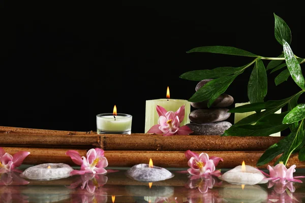 Wellness-Stillleben mit Blumen und Kerzenschein auf schwarzem Hintergrund — Stockfoto