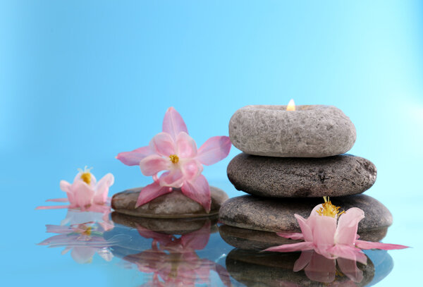 Stack of spa stones with flowers on blue background