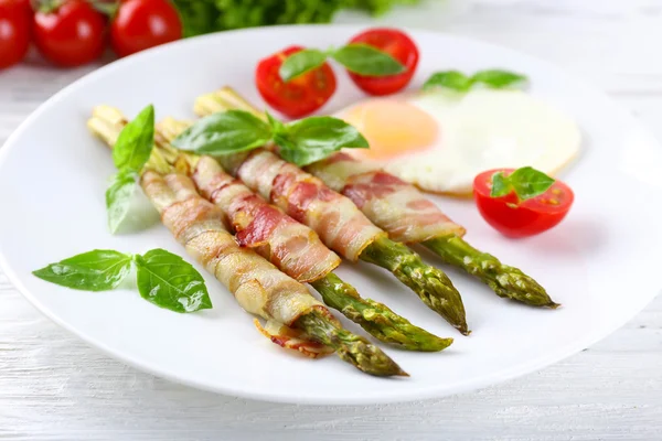 Dish of asparagus with bacon and egg in plate on table, closeup — Stock Photo, Image