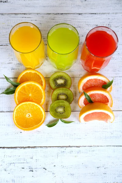 Okulary z różnych soków z owoców i mięta na drewniane tła — Zdjęcie stockowe