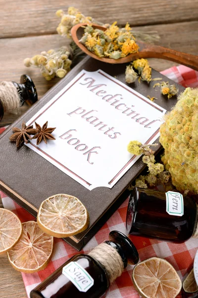 Medicinal plants book with dried herbs and bottles on table close up — Stock Photo, Image