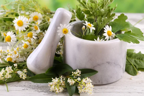 Örter och blommor med murbruk, på träbord, på ljus bakgrund — Stockfoto