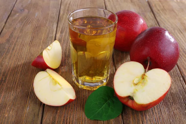 Glas äppeljuice med röda äpplen på träbord, närbild — Stockfoto