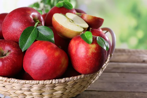Rött äpple i rotting korg på träbord, närbild — Stockfoto