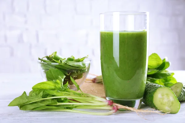 Friska gröna smoothie på träbord på vit vägg bakgrundzdravé zelené smoothie na dřevěný stůl na bílé zdi pozadí — Stockfoto