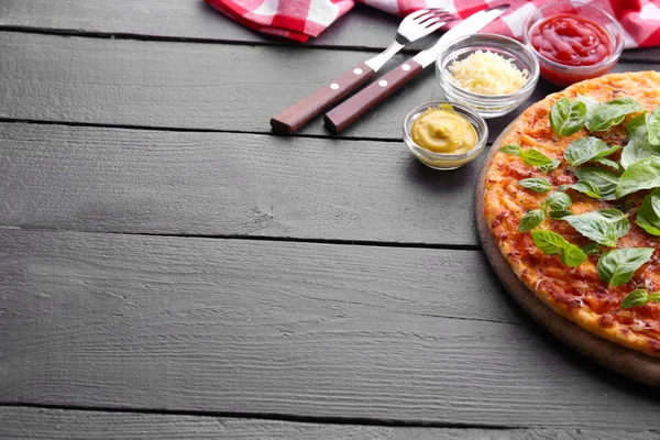 Ahşap arka plan üzerinde kesme tahtası üzerinde Fesleğenli pizza — Stok fotoğraf