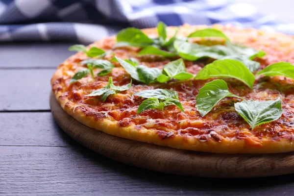 Pizza met basilicum op houten tafel, close-up — Stockfoto