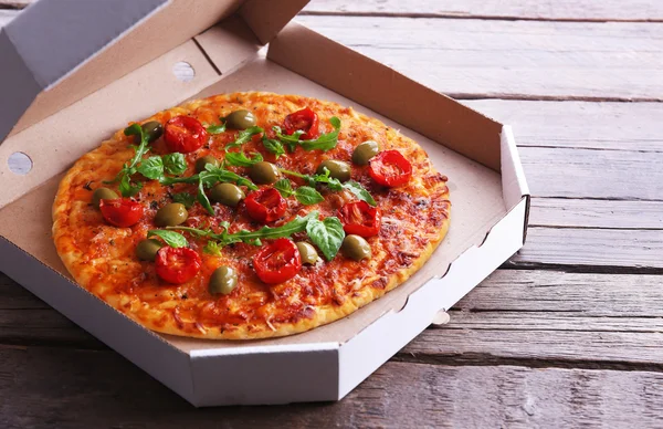 Пицца в коробке на деревянном столе, крупным планом — стоковое фото