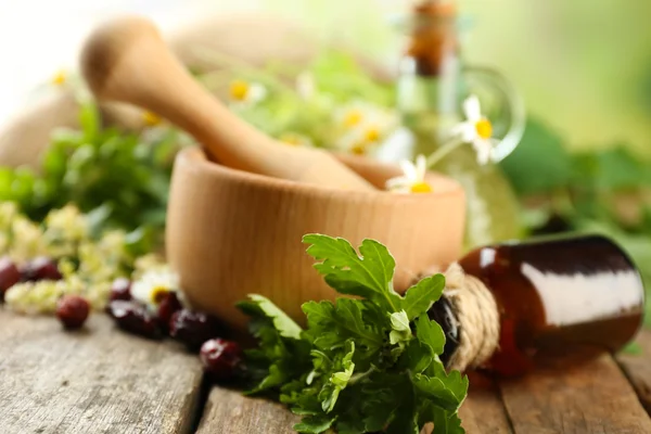 Herbes, baies et fleurs au mortier, sur fond de table en bois — Photo