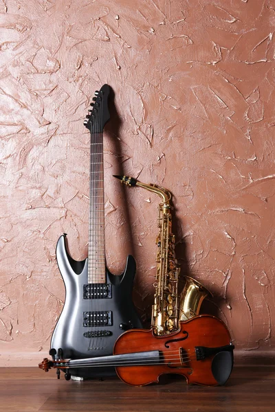 Elektrische gitaar, saxofoon, viool op bruin muur achtergrond — Stockfoto