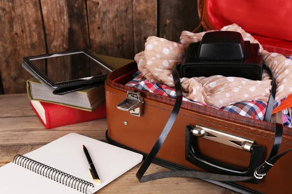 Packing suitcase for trip on wooden background — Stock Photo, Image