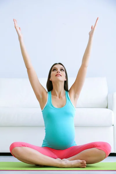 Femme enceinte faisant de l'exercice sur tapis vert dans la chambre — Photo