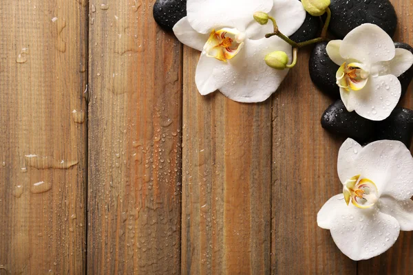 スパ石や木製の背景上の蘭の花 — ストック写真