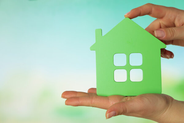 Female hands with model of house on blurred background