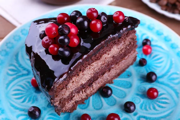 Delicious chocolate cake with berries on plate on table close up — Stock Photo, Image