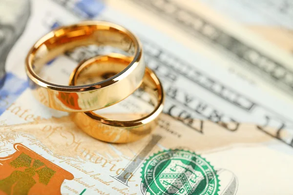 Fedi nuziali dorate sullo sfondo delle banconote. Matrimonio di convenienza — Foto Stock