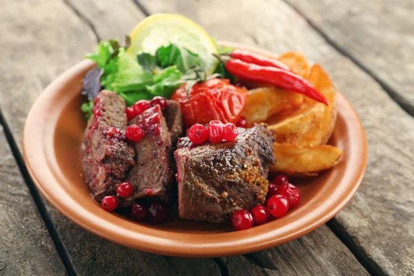 Carne assada saborosa com molho de cranberry, salada e legumes assados na placa, no fundo de madeira — Fotografia de Stock