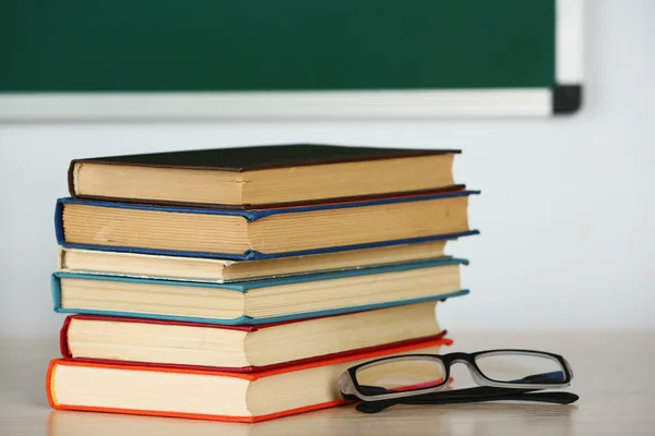 Bainha de livros e óculos na mesa em classe — Fotografia de Stock