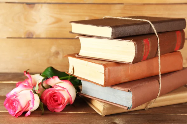 Tied books with pink roses on wooden background — Stock Photo, Image