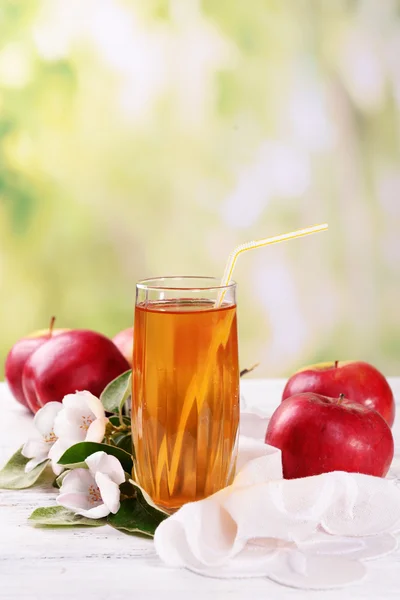 Vaso de zumo de manzana y manzanas sobre mesa de madera, sobre fondo natural — Foto de Stock