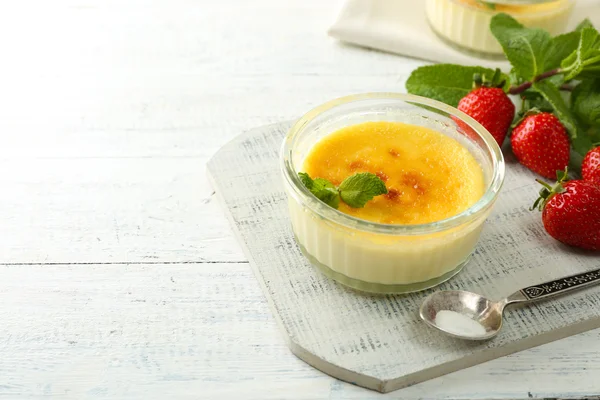 Creme brulee tatlı taze çilek ve renk ahşap zemin üzerine nane yaprakları ile