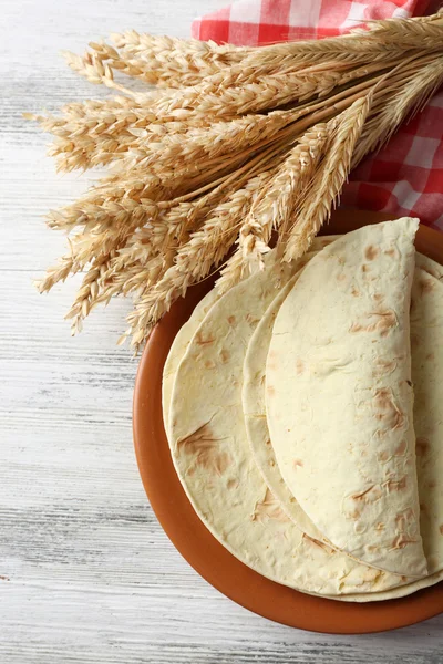 Stapel van zelfgemaakte volkoren meel tortilla op plaat, op houten tafel achtergrond — Stockfoto