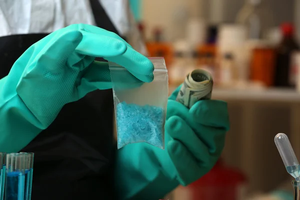 Chemists holding plastic bag with blue methamphetamine and money in laboratory — Stock Photo, Image