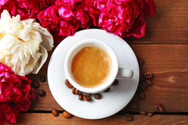 Состав с чашкой кофе и пионскими цветами на деревянном фоне — стоковое фото