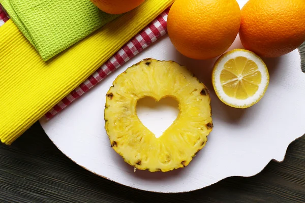 Pineapple slice with cut in shape of heart and different fruits on table close up — Stock Photo, Image