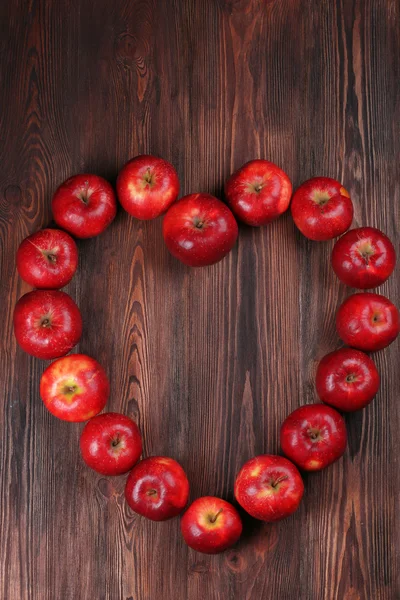 Manzanas rojas maduras en forma de corazón sobre fondo de madera — Foto de Stock