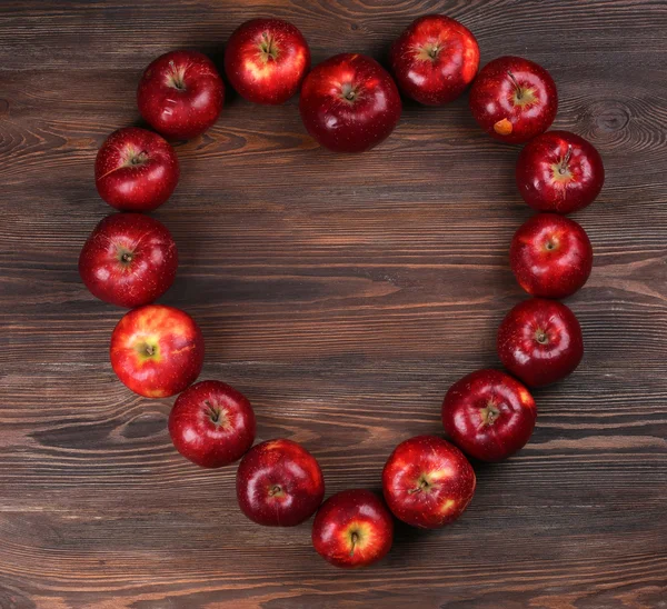 Manzanas rojas maduras en forma de corazón sobre fondo de madera — Foto de Stock