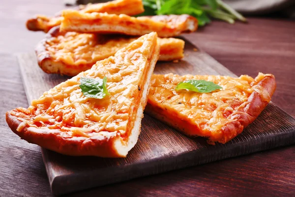 Scheiben leckere Käse-Pizza mit Basilikum auf dem Tisch aus nächster Nähe — Stockfoto