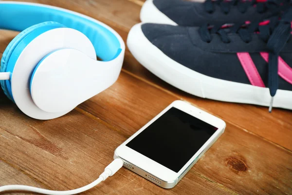 Zapatos deportivos y auriculares sobre fondo de madera — Foto de Stock