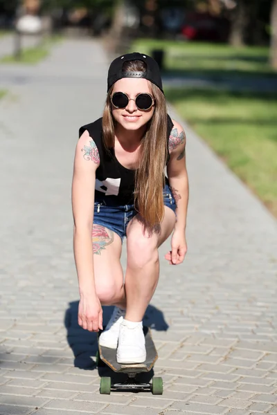 Hermosa chica tatuada con monopatín, al aire libre — Foto de Stock