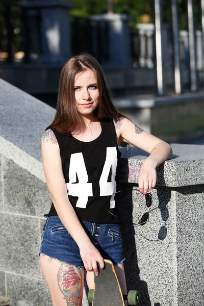 Menina tatuada bonita com skate, ao ar livre — Fotografia de Stock