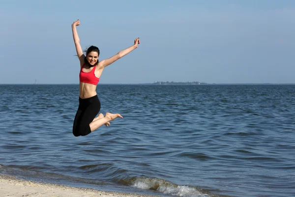 Jovem mulher pulando na praia — Fotografia de Stock
